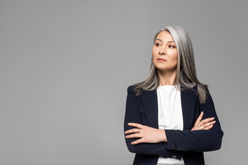 Obraz premium confident asian stylish businesswoman with grey hair and crossed arms isolated on grey