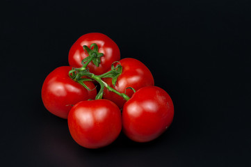 a bunch of five vine tomatoes on dark background