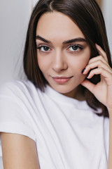 Elegant brunette girl with dark eyes expressing interest. Studio shot of glamorous confident woman posing with gently smile.