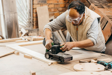 Worker grinds the wood of angular grinding machine