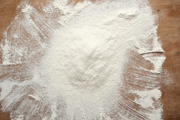Naklejka premium slide of white wheat flour sprinkled on a brown wooden table