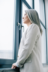 attractive asian businesswoman with grey hair looking through window