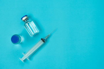 Table top view accessories healthcare & medical with coronavirus background concept.Anti retroviral vaccine bottle with Syringe on blue paper.Flat lay items for doctor using treat patient Covid-19.