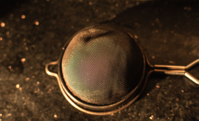 An Indian steel tea strainer kept upside down in a kitchen.
