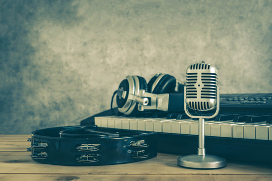 Music instruments concept background. Close up group of musical tools the vintage michophone, headphone,tambourine on brown wooden and grey cement.copy space for creative design text.