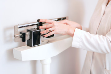 Closeup view of woman's hand adjusting professional balance weight scale. View is closeup, with a...