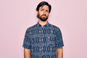 Young handsome hispanic bohemian man wearing hippie style over pink background looking sleepy and tired, exhausted for fatigue and hangover, lazy eyes in the morning.