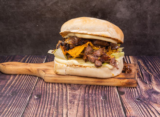 Tasty fresh burger with beef, cheese, lettuce and sauce, on a wooden board