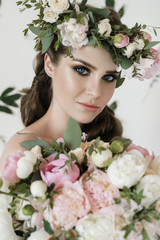 The bride holds a wedding bouquet, wedding dress, wedding details. wedding bouquet of peonies. Bride with snatural wreath of fresh flowers. Hairstyle from volumetric braids. lifestyle, fashion