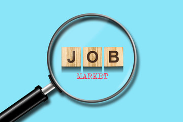 Job market. The inscription on the wooden blocks on a blue background. View through a magnifying glass. Business.