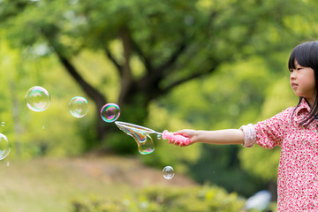 春の公園でシャボン玉を遊んでいる可愛い子供