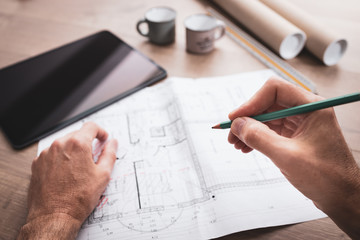 Tablette, mains et plans dans un environnement  d'architecte travaillant sur un projet de...