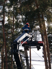 Electrical work, an electrician restores broken wires standing in the basket of a specialized machine. Restoration work, energy, industrial production.