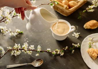 Croissants and coffee with milk on a black background with flowering branches of cherry
