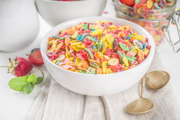 Colorful fruit cereal flakes. Multicolored fruit breakfast corn flakes, with various fruit taste, with milk and fresh berries on white table. Traditional american morning snack