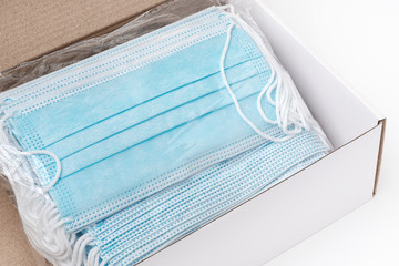 Package of surgical face masks with rubber ear straps in cardboard box. Close-up view of large lot...