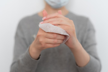 woman in a gray hoodie wipes her hands with a napkin on a white background