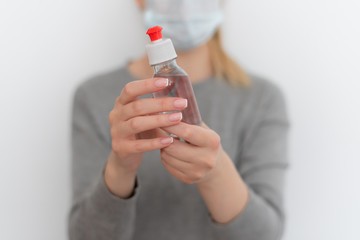 girl in a gray hoodie holds bottles with transparent liquid in her hands on a white background
