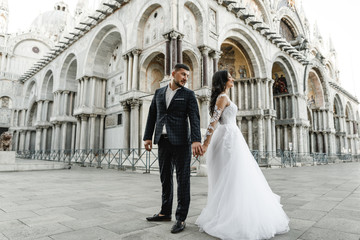 Obraz premium bride and groom on the background of a historic building,bride and groom walk the streets of the old city of venice,newlyweds dance,european wedding,quarantine wedding