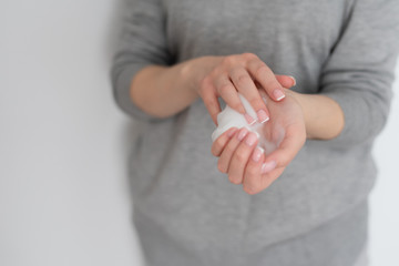 girl in a gray hoodie applies foam on hands on a white background