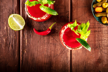 Bloody Mary cocktail with tomato juice, lime, and celery, overhead shot on a rustic background with...