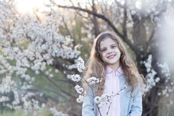 Portrait of a little girl with wavy hair in a flowery Park