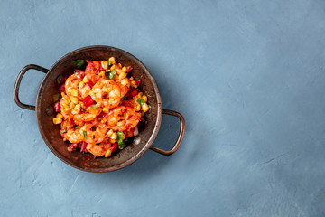 Spicy shrimps with corn in a copper pan, shot from above with copy space