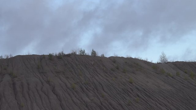 sand roadside embankment (agger; road fill) is cut by water flows. Water erosion of soil and damage to road construction. It is required to fix the ground with grass cover, herbage
