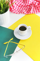 a coffee mug stands on a notebook, next to it lies a phone, pens 