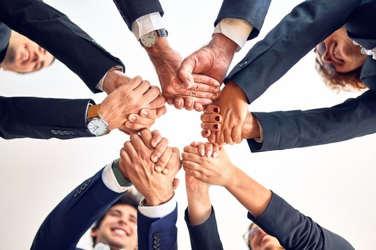 Group of business workers smiling happy and confident. Standing on a circle with smile on face doing symbol with hands and arms together at the office.