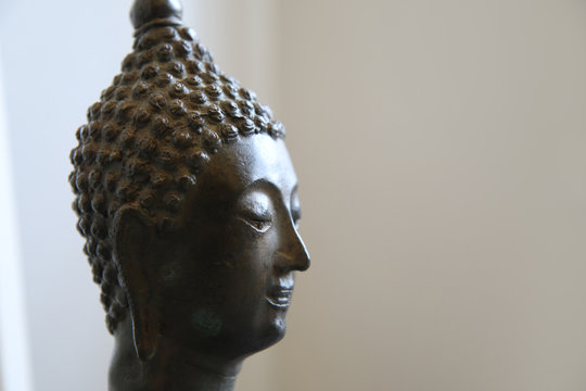 Budda, primo piano di testa in bronzo di provenienza tailandese, scultura su fondo bianco, spazio per testo 