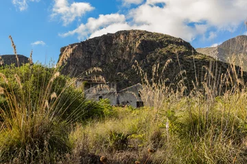 Foto op Canvas Mediterranean landscape of Sicily, Italy. View shot in Zingaro Nature Reserve. In the background old hut/cottage house. Mix of rock, coast, sky, mountain, plants, flora, architecture and hill.  © Tomasz