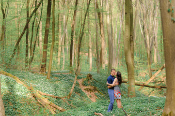 Obraz premium Young beautiful couple in love in the forest. A couple is hugging near a ravine among the trees. Free space.