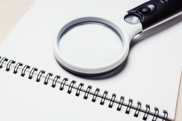Magnifier for research on an open notebook. Business plan analysis concept.