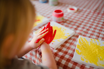 kleines Kind malt mit bunter Fingerfarbe 