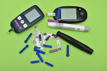 2 Diabetes set with glucometer, lancet, spare needles on green background 