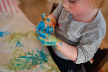 Kleinkind malt mit bunter Fingerfarbe, matschen mit bunter Farbe