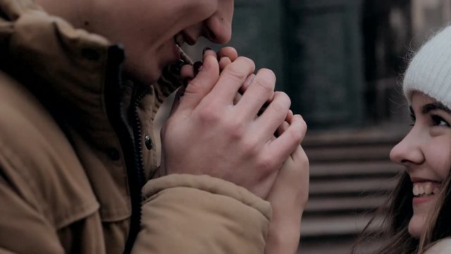 Man holds girl's hands and warms them smiling