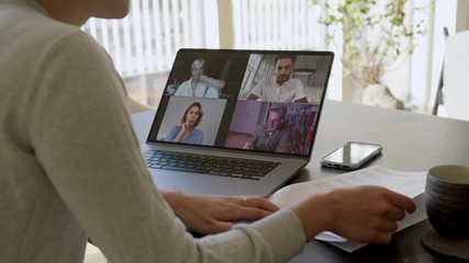 Woman at home listening to the conversation of colleagues and looking at a document during a video conference. Group of business men and women meeting online over a video call to discussing new strate - Powered by Adobe