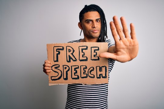 Young African American Man With Dreadlocks Holding Banner With Free Speech Message Protest With Open Hand Doing Stop Sign With Serious And Confident Expression, Defense Gesture