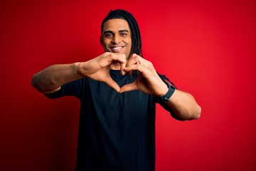 Young handsome african american afro man with dreadlocks wearing casual t-shirt smiling in love doing heart symbol shape with hands. Romantic concept.
