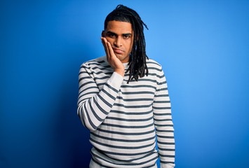 Young handsome african american afro man with dreadlocks wearing casual striped sweater thinking looking tired and bored with depression problems with crossed arms.