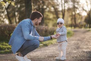 Adorable little gilr spend time with her father. Dad and daughter walk in the park. Stylish family. Happy little girl in sunglasses. Dad give some present to daughter