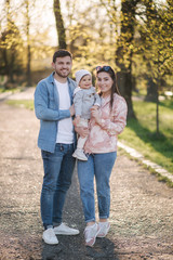 Portrait of happy family in the park. Father mother and litthe daughter. Adorable little with with mom and dad. Young family, Handsome dad and attractive young mom. Happy Mother's Day