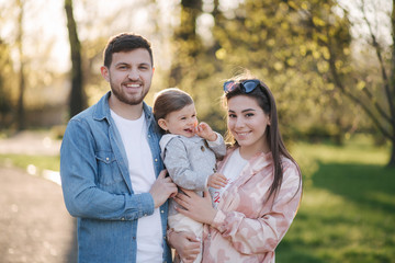 Portrait of happy family in the park. Father mother and litthe daughter. Adorable little with with mom and dad. Young family, Handsome dad and attractive young mom. Happy Mother's Day
