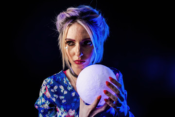 Infantile girl on a black background in blue light