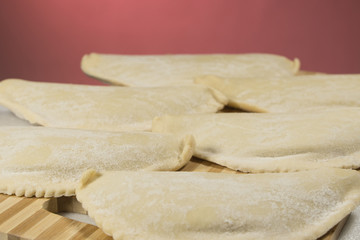 Cold chebureks with stuffing, on wooden blackboard.