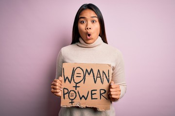 Young asian activist girl asking for women rights holding banner with woman power message scared in shock with a surprise face, afraid and excited with fear expression