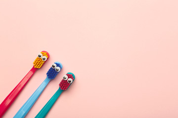 Kids toothbrushes of different colors on a pink background. Teeth and oral hygiene for children
