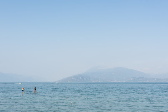 Friends Paddleboarding In Sea Against Clear Sky